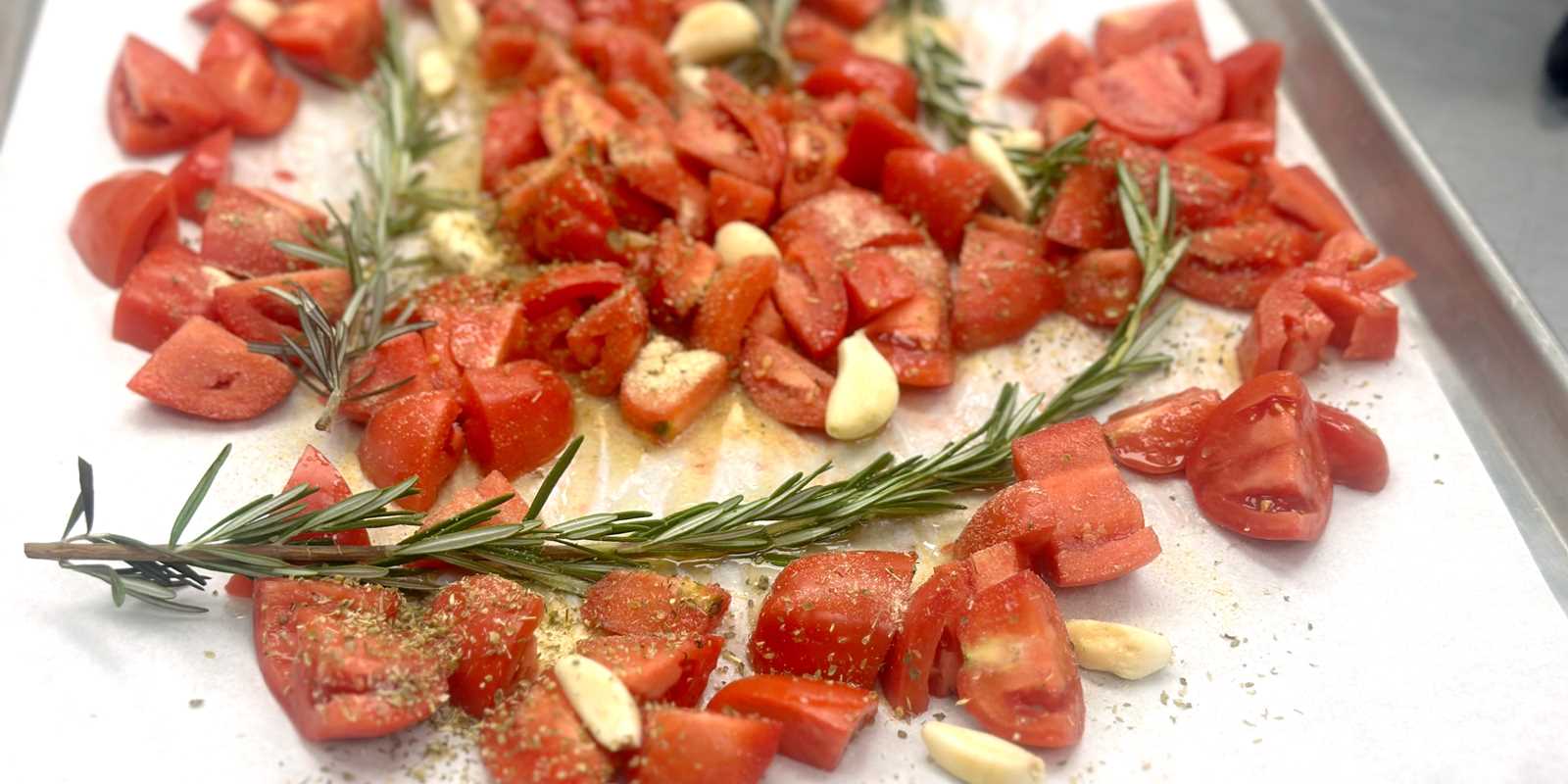 tomatoes, rosemary and garlic on a roasting sheet