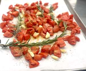 tomatoes, rosemary and garlic on a roasting sheet